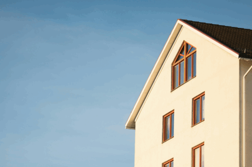 Upwards shot of a home displaying five windows with light blue sky in the background