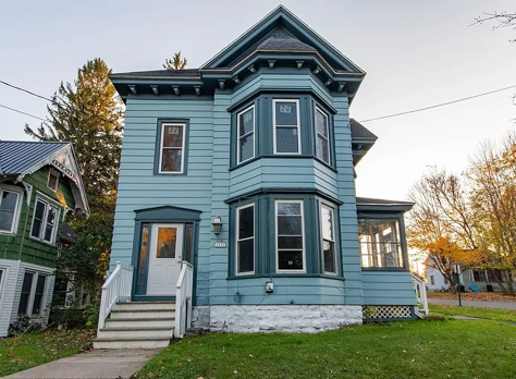 A blue house with dark green trimming and a white door