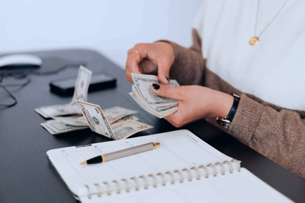 Woman counting passive income collected over a table with a notebook and pen