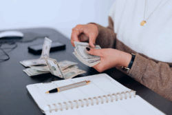 Woman counting passive income collected over a table with a notebook and pen